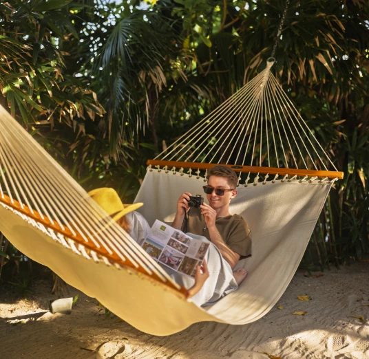 a man lying in a hammock with a camera