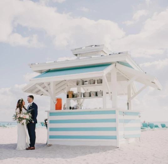 a man and woman standing in front of a beach kiosk