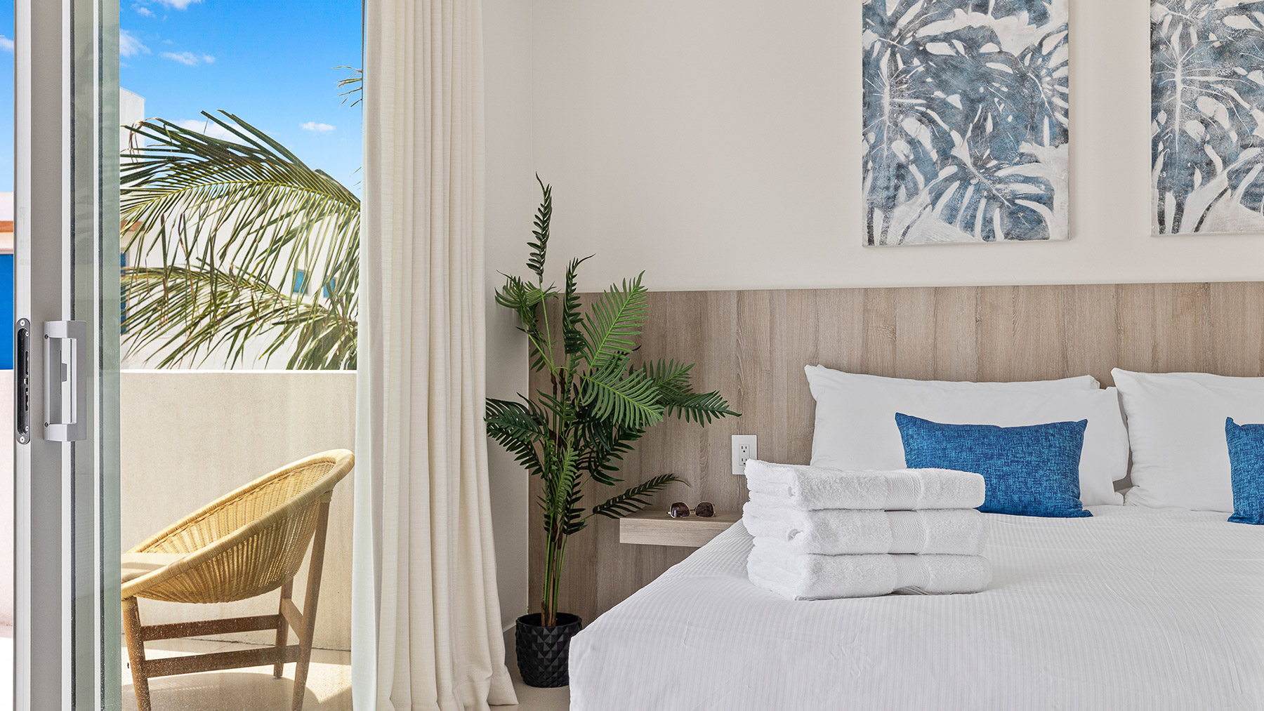 a bed with white towels and a plant in a room with a balcony