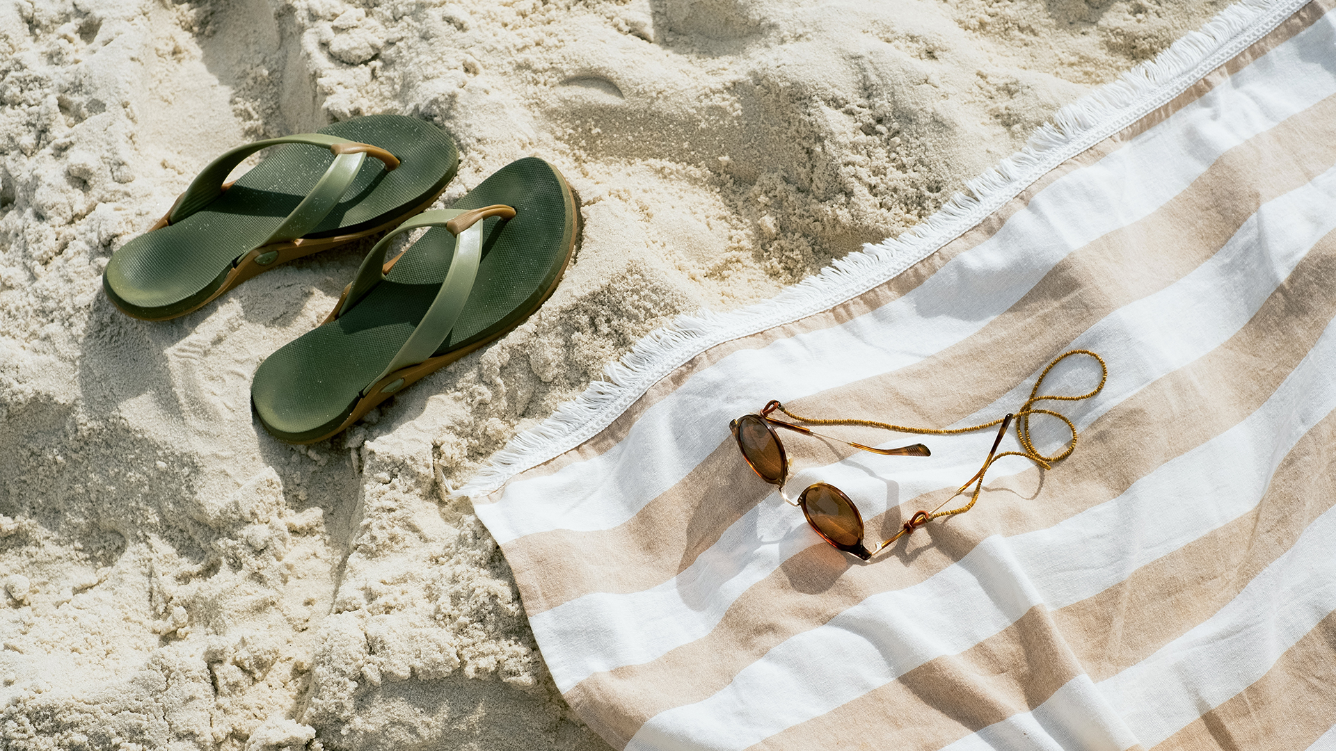 a towel and sandals on sand