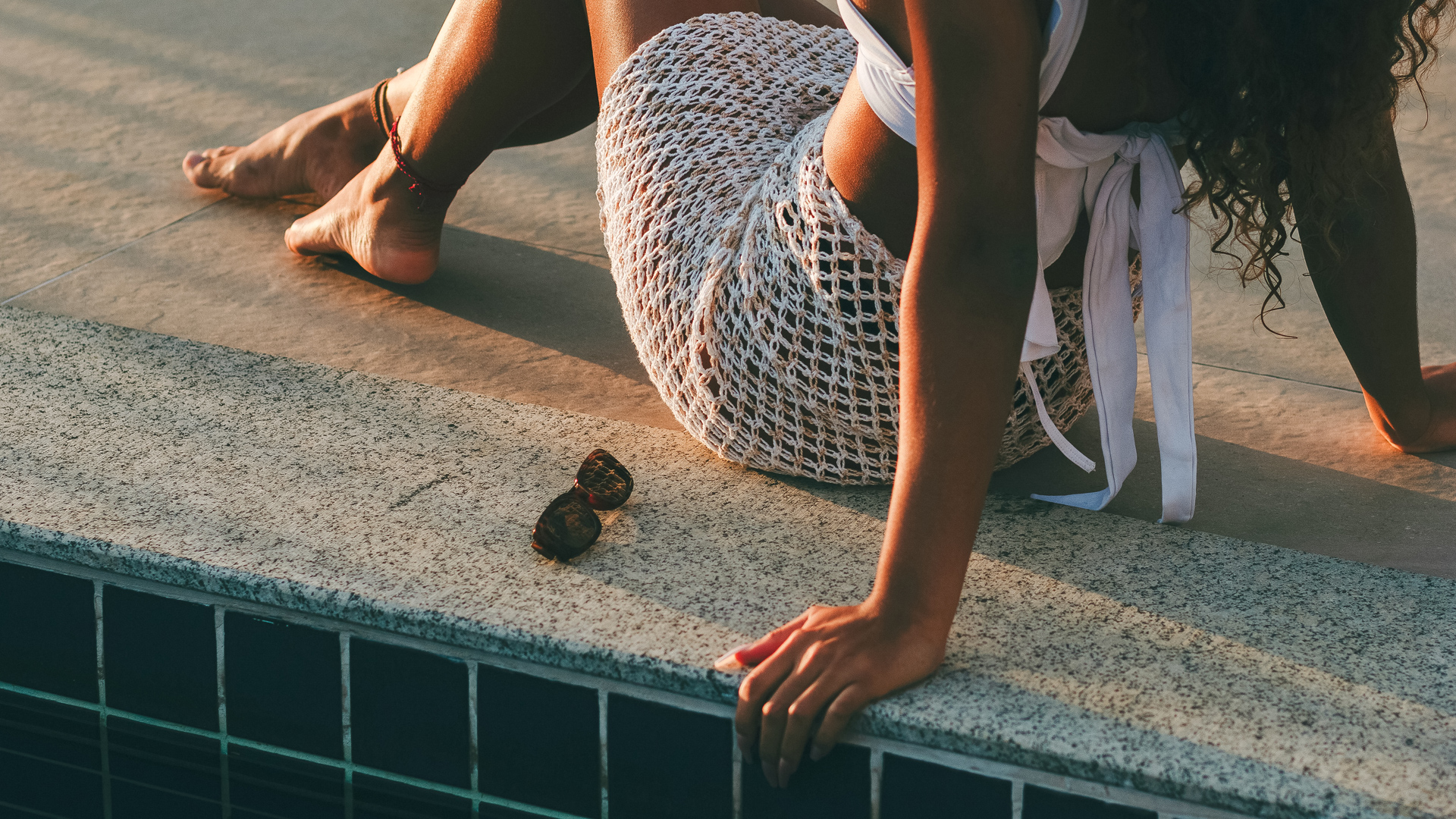 a woman sitting on a ledge with sunglasses