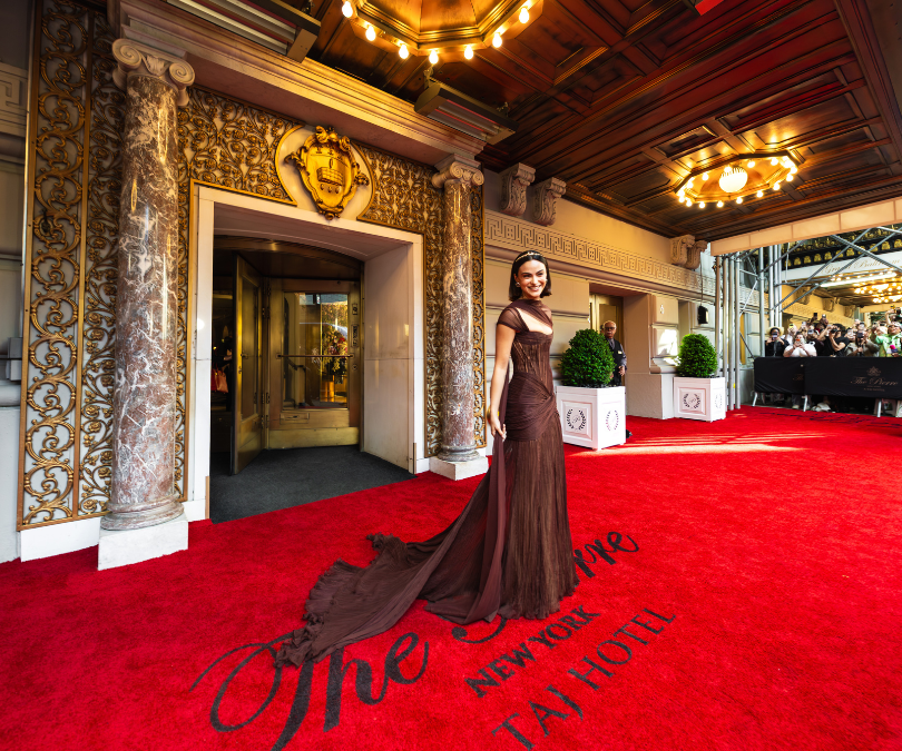 a woman in a long dress on a red carpet outside of a building