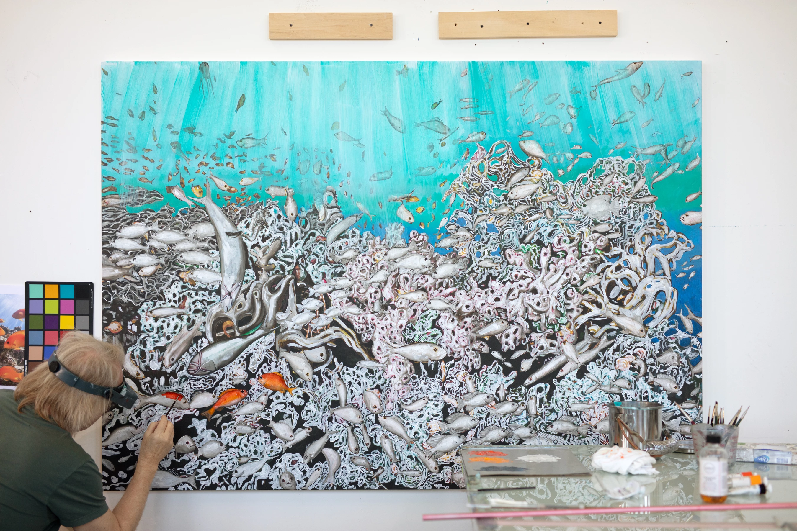 a person painting a large painting of fish