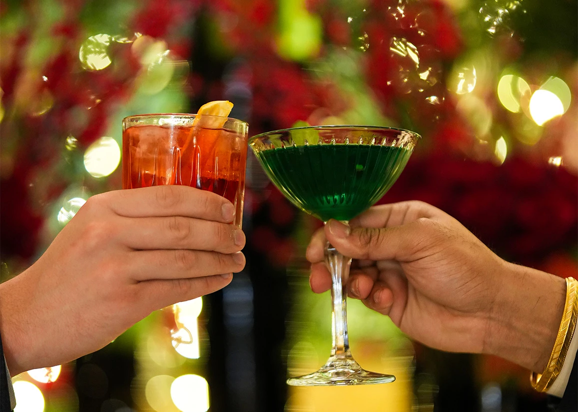 two hands holding glasses with drinks