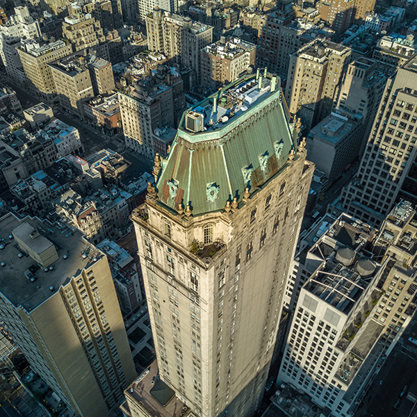 a tall building with a green roof and many tall buildings