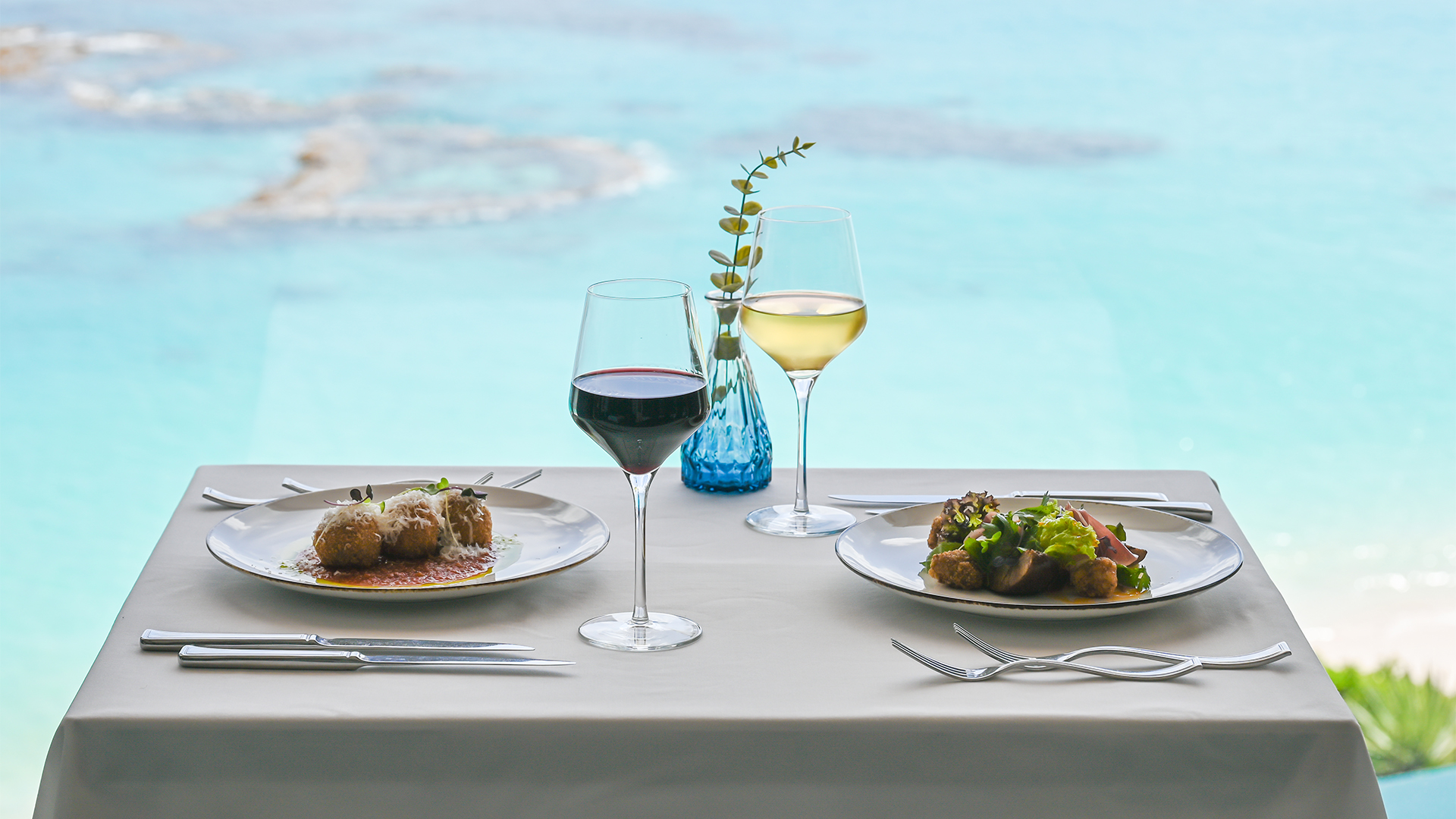 a table with plates of food and wine glasses