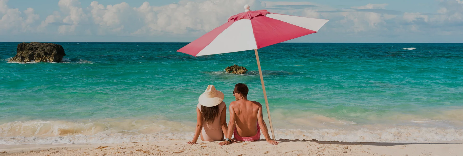 a couple sitting on a beach under an umbrella