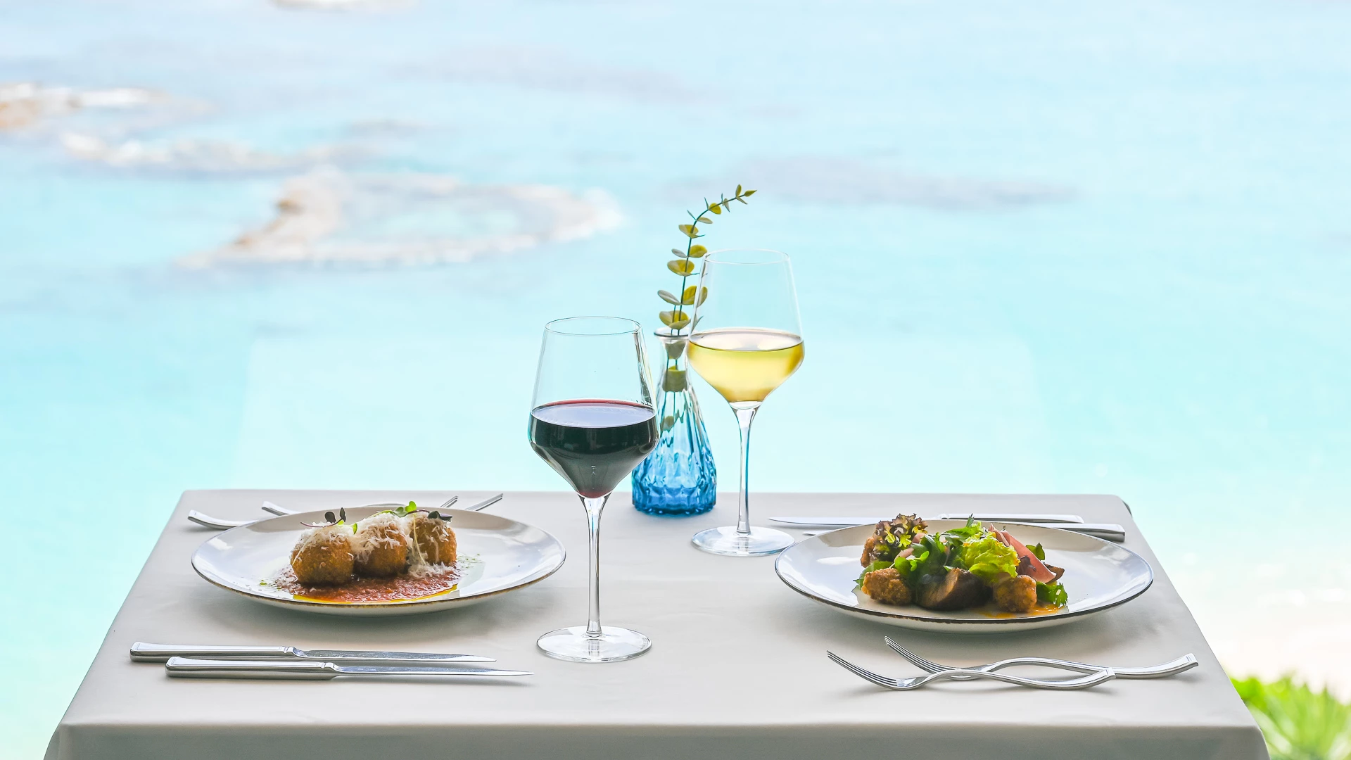 a table with plates of food and wine glasses