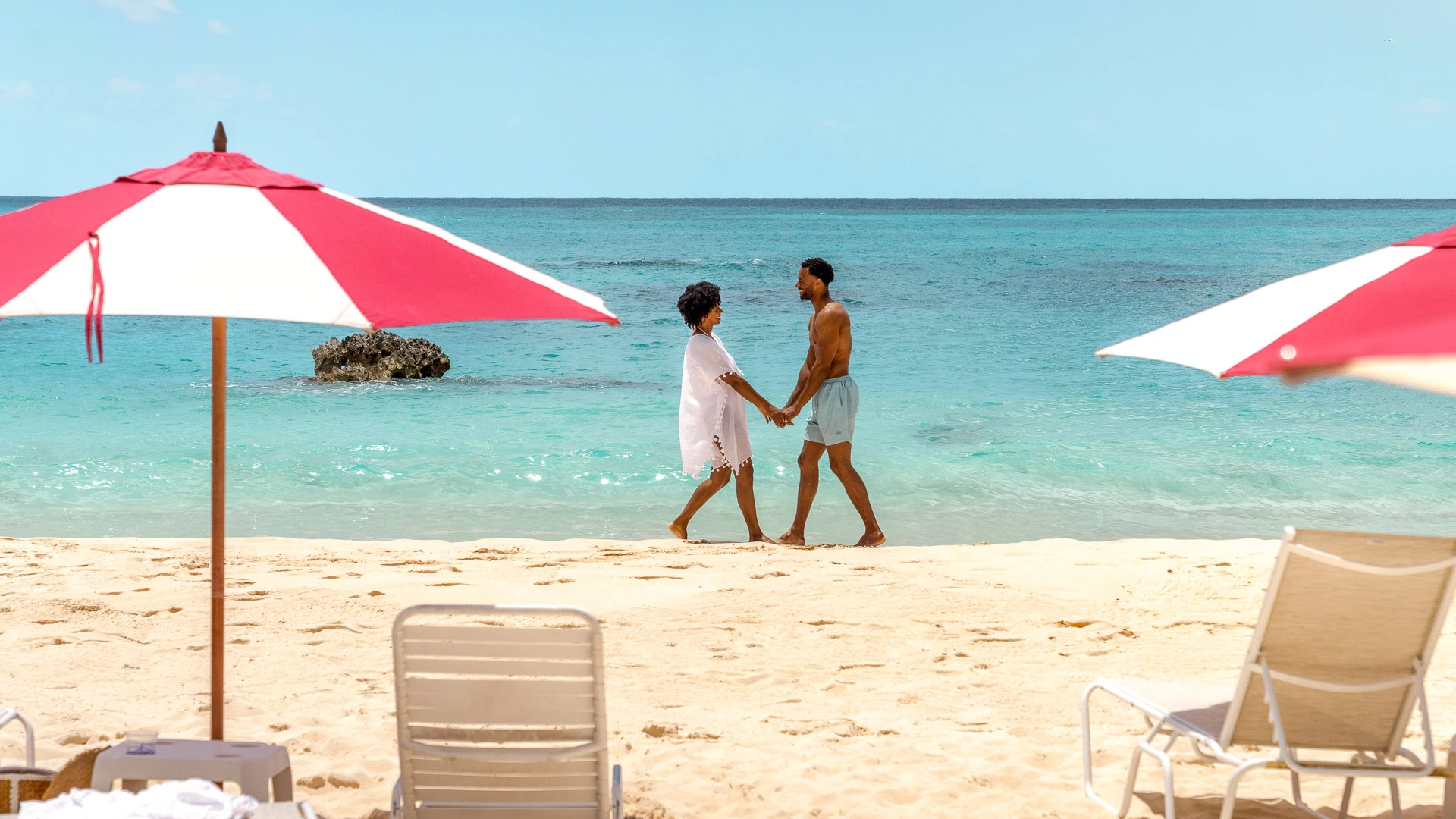 a man and woman holding hands on a beach