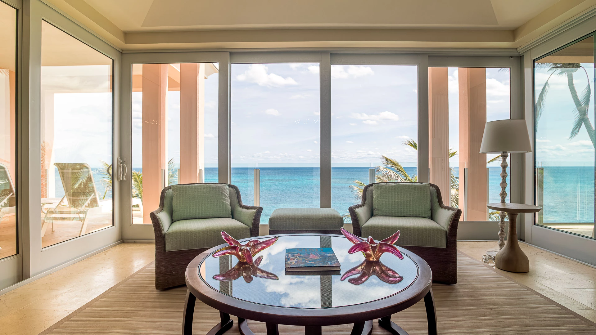 a room with chairs and a table with a view of the ocean