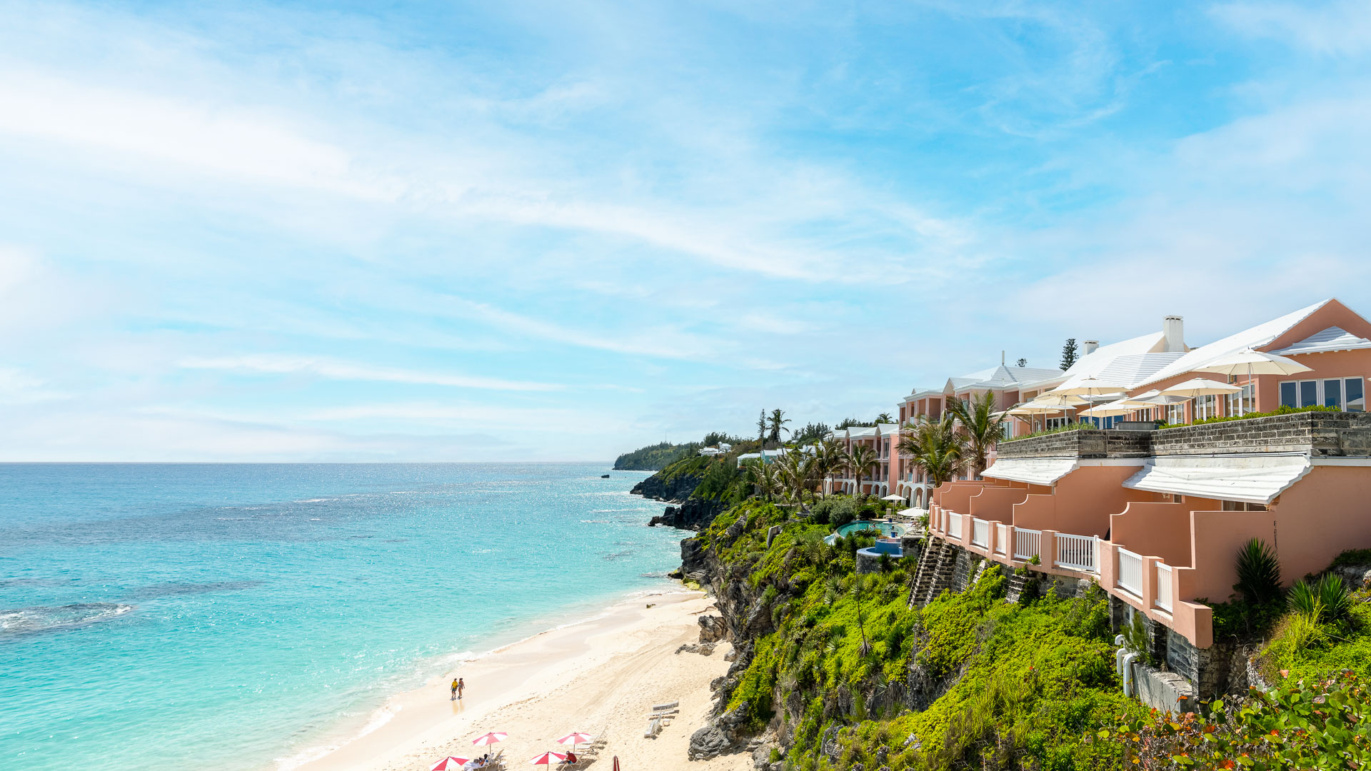 a beach with buildings and umbrellas