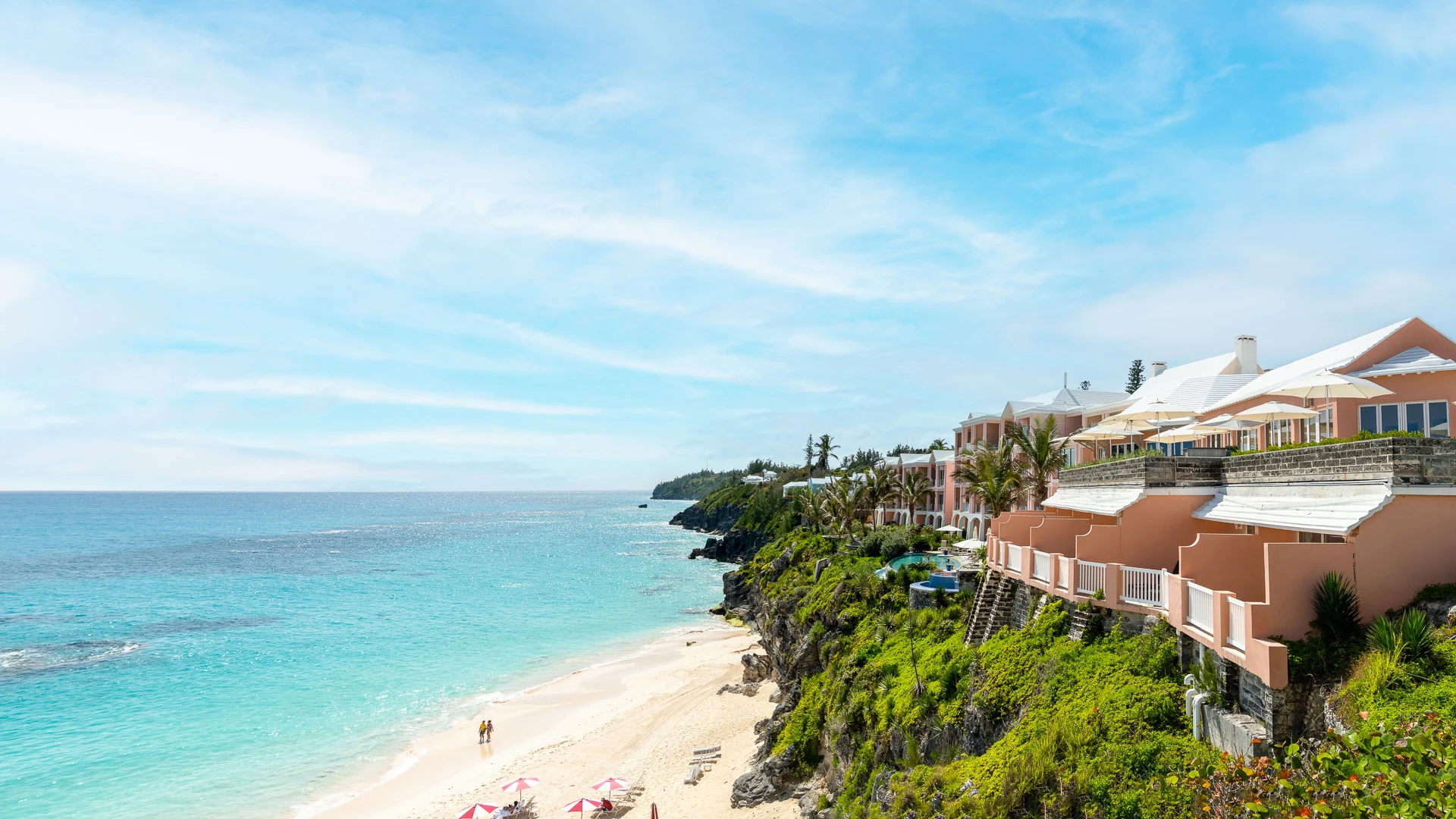 a beach with buildings and umbrellas