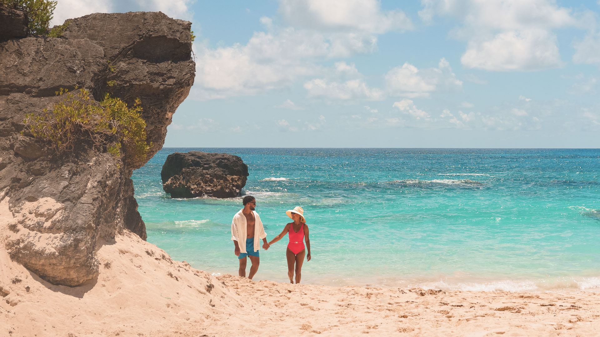 a man and woman holding hands on a beach