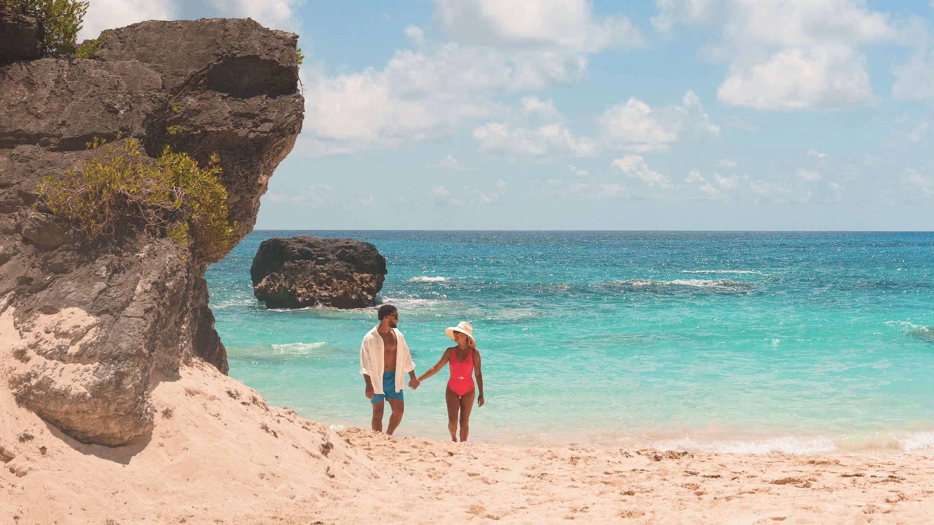a man and woman holding hands on a beach