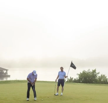 a group of men holding golf clubs and a flag on a golf course