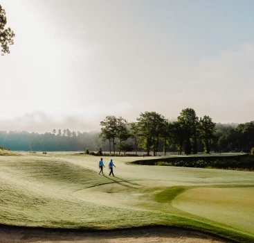 a group of people walking on a golf course