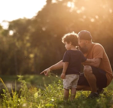 a man and child standing in grass
