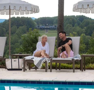 a man and woman sitting on chairs by a pool
