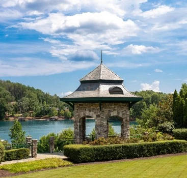 a stone gazebo next to a body of water