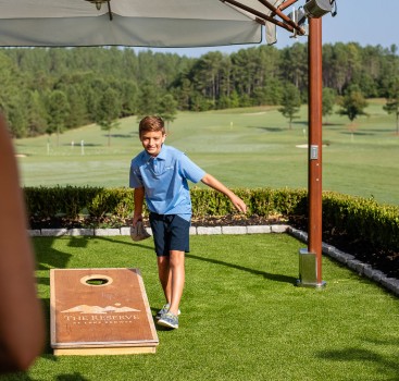 a boy throwing a bag toss