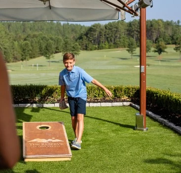 a boy throwing a bag toss