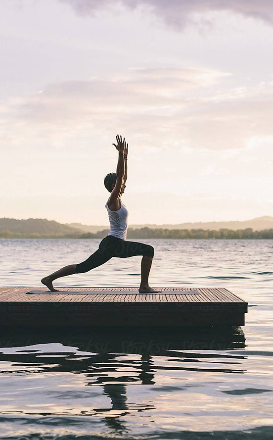 a woman doing yoga on a dock in the water