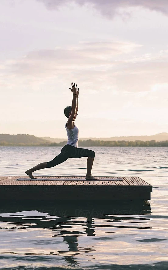 a woman doing yoga on a dock in the water