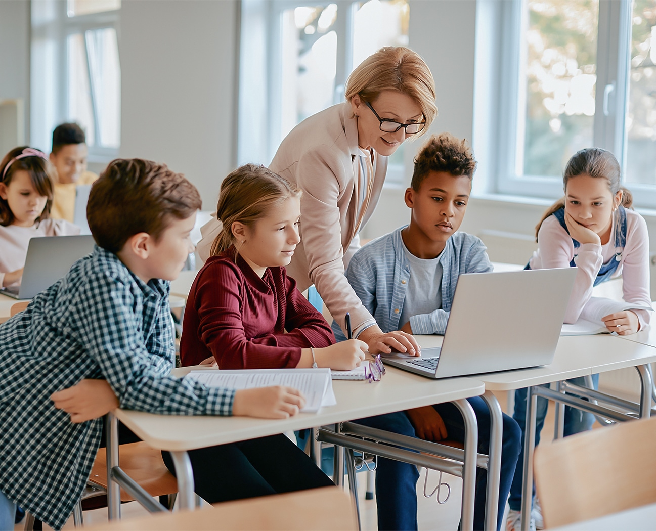 a group of kids sitting at desks with a laptop