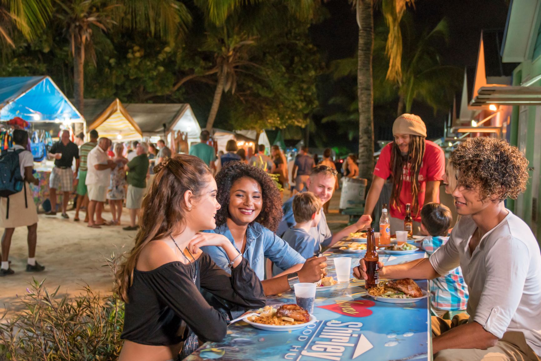 a group of people sitting at a table with food and drinks