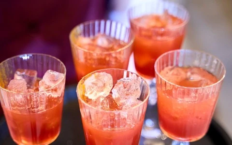 a group of glasses with red liquid and ice