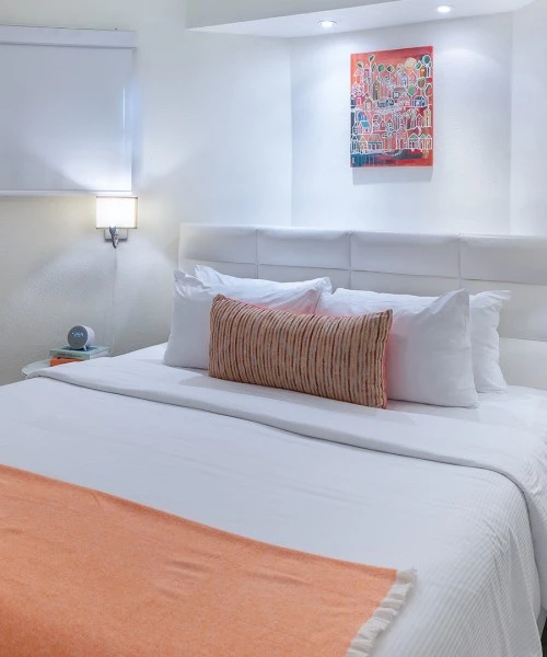 a bed with a white headboard and orange blanket