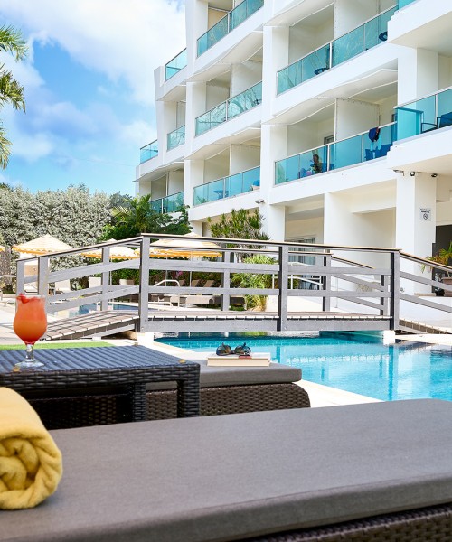 a pool with a glass of liquid and a cocktail next to it