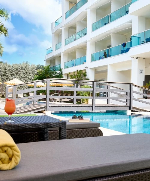 a pool with a glass of liquid and a cocktail next to it