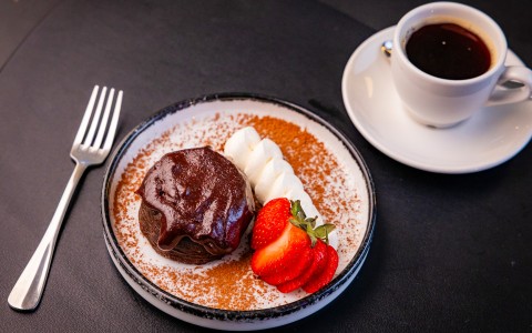 a plate of dessert with strawberries and a cup of coffee