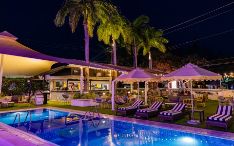 a pool with lounge chairs and umbrellas and palm trees