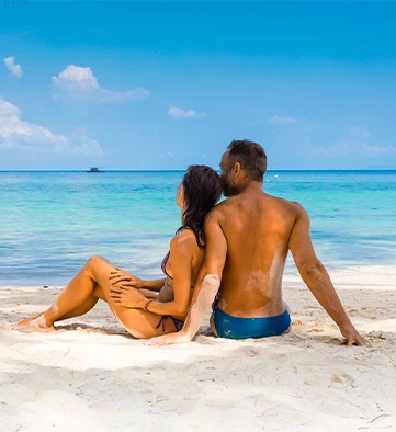 a couple sitting on the beach covered in sand
