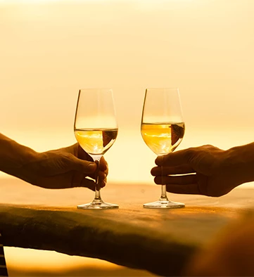two glasses of white wine on a wooden table