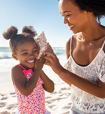 a woman with her child listening to a conch shell