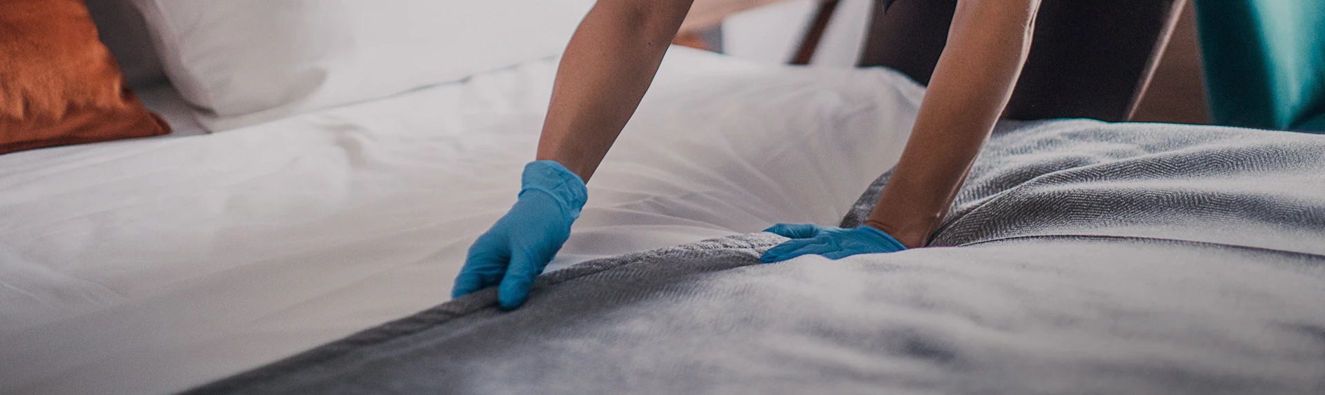 a person with gloves on making a bed