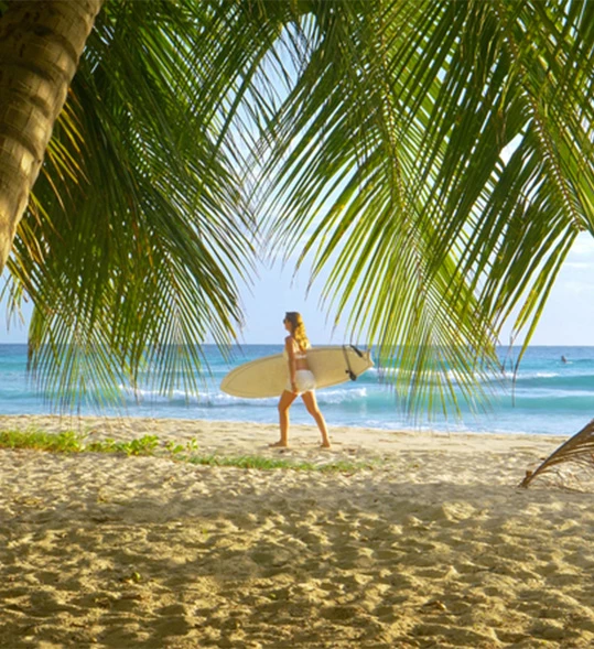 a woman walking on a beach with a surfboard