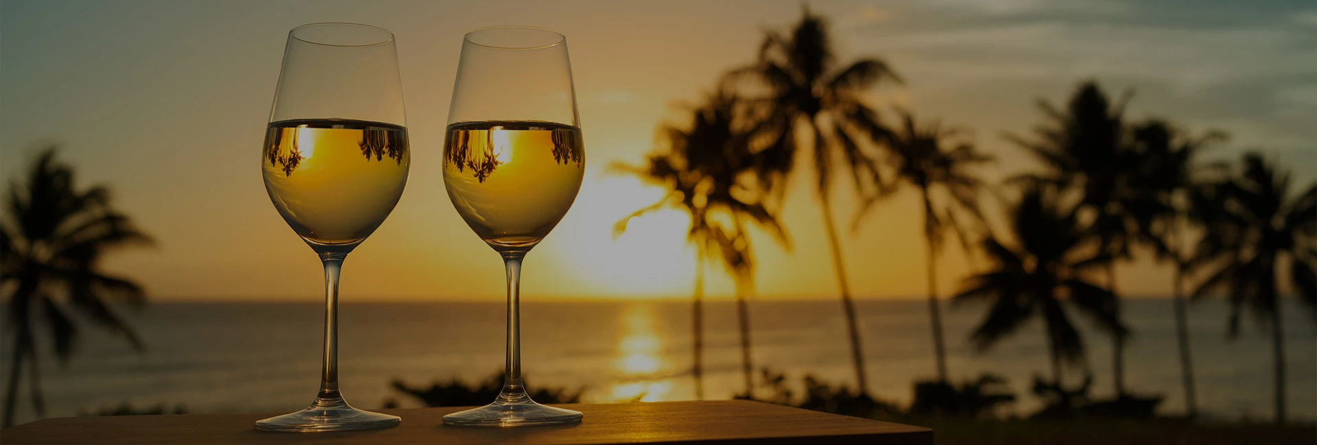 a glass of wine on a table with palm trees in the background