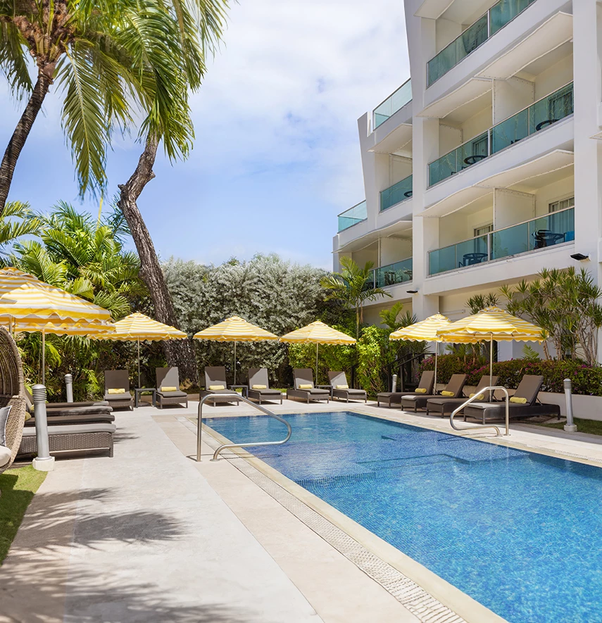 a pool with umbrellas and chairs in front of a building