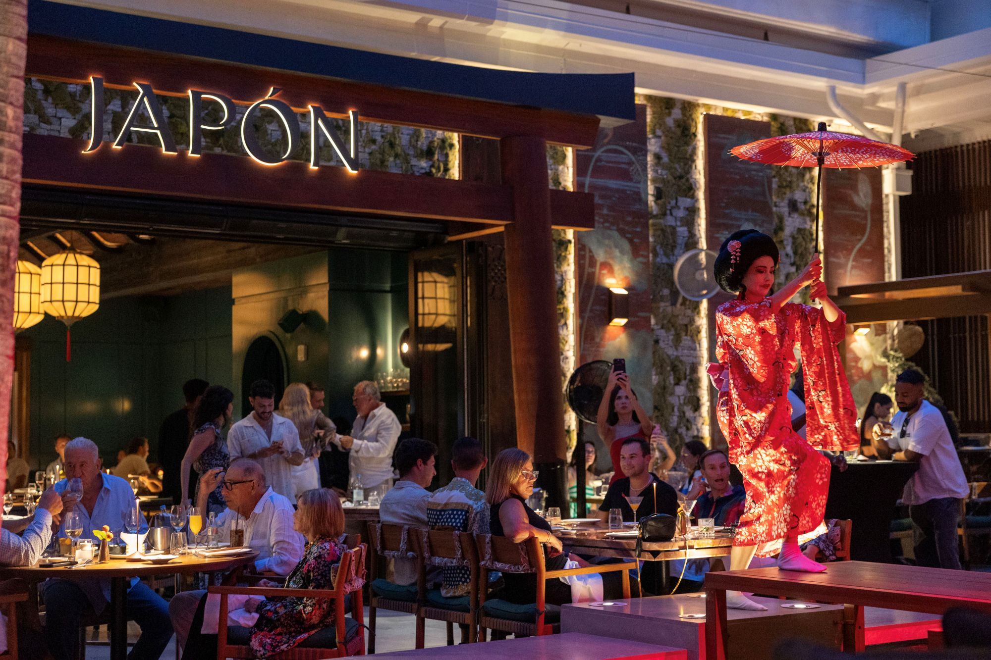 a woman in a red dress with an umbrella in front of a restaurant