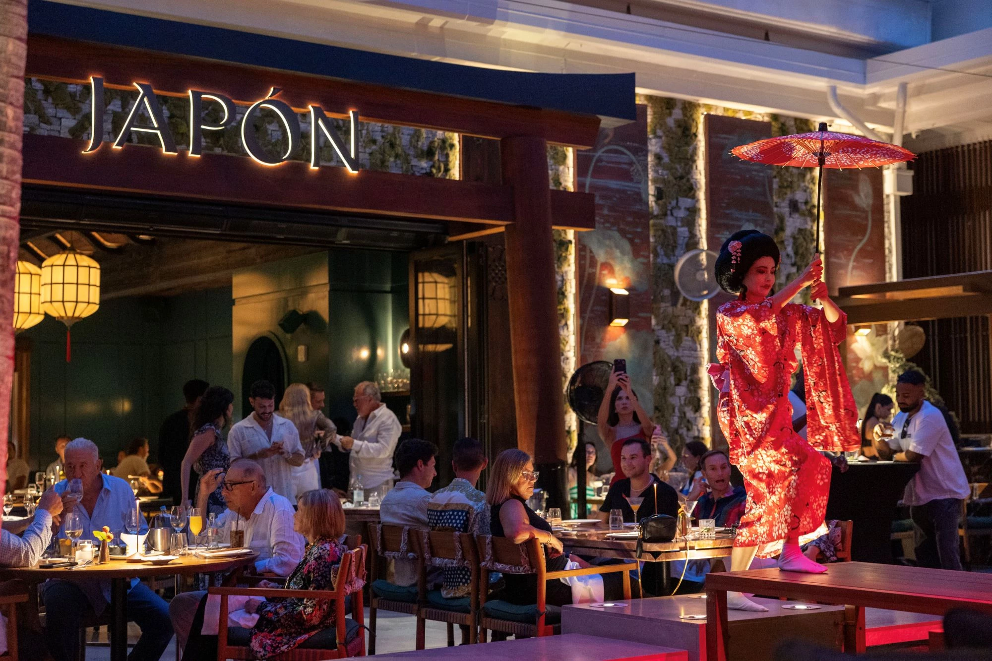 a woman in a red dress with an umbrella in front of a restaurant