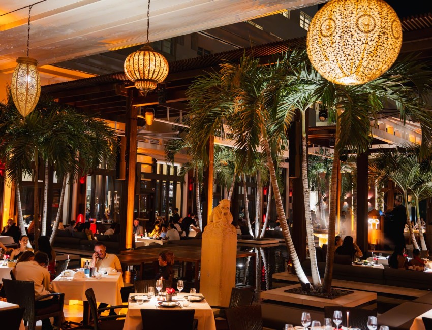 a restaurant with palm trees and people sitting at tables