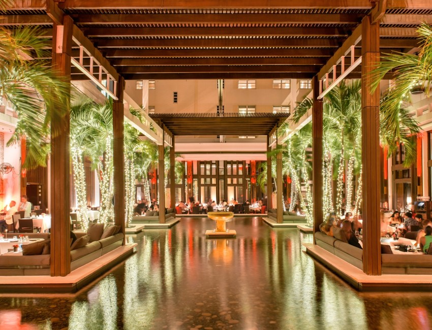 a pool with lights and trees in front of a building