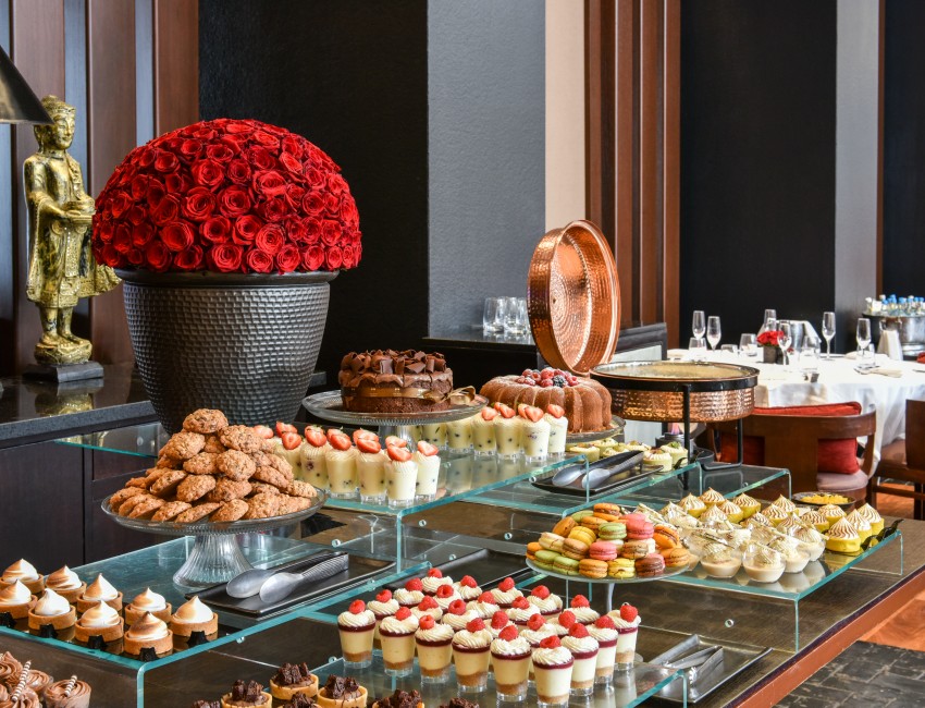 brunch buffet station with a variety of desserts and a red rose bouquet