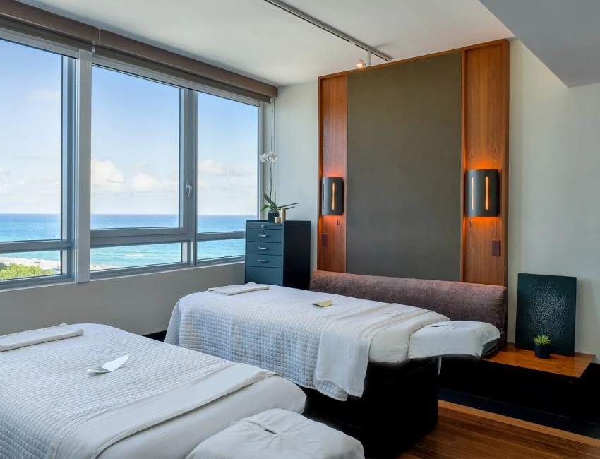 two beds set up for spa service overlooking the view of the beach during the day