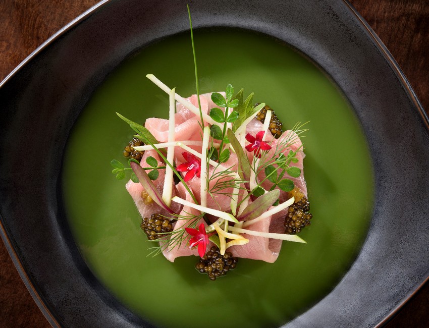 close up of a sashimi dish served on top of green finishing sauce