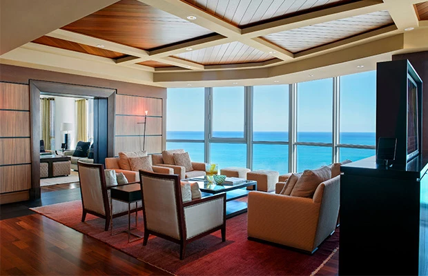 a living room area with chairs, sofa, and coffee table and a view of the clear blue ocean